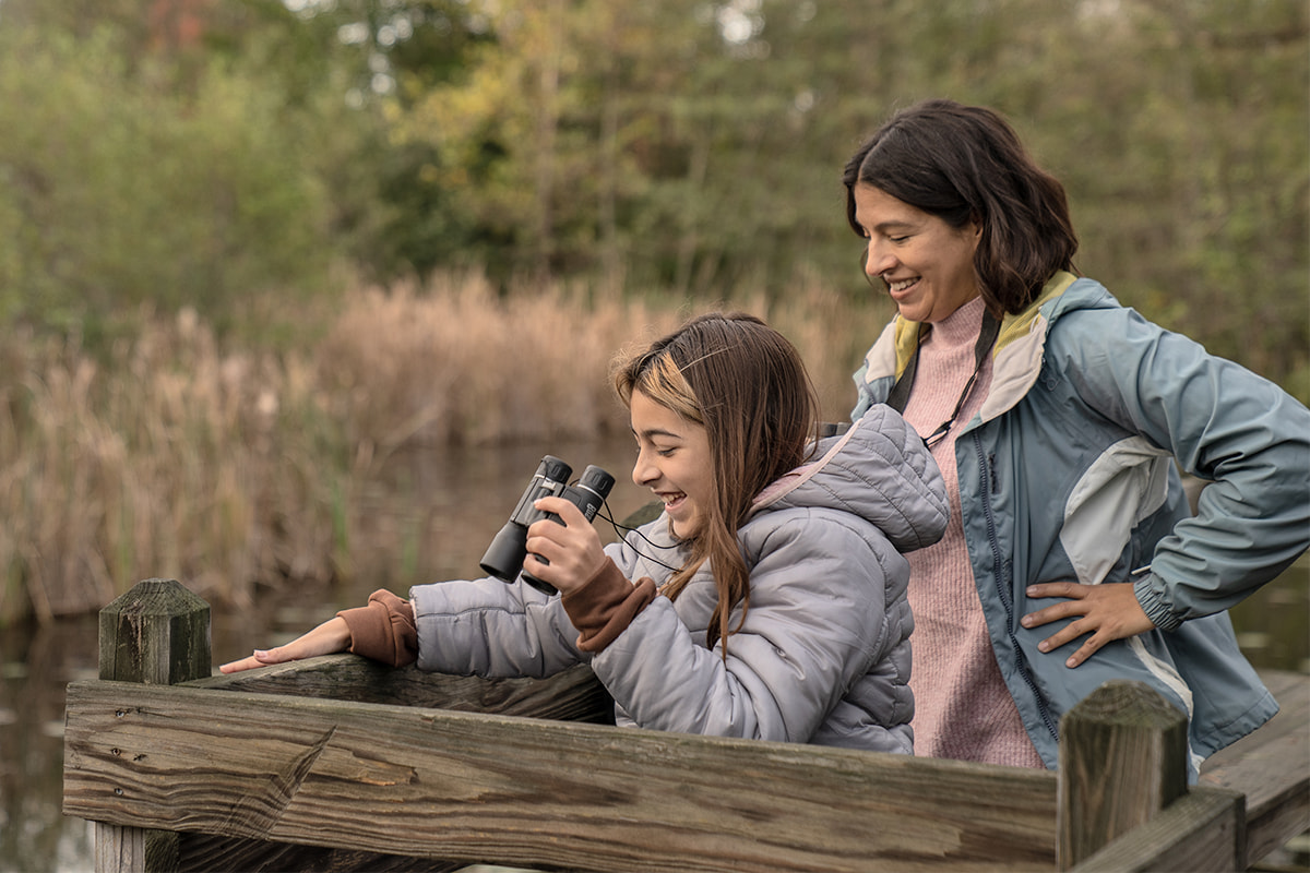 Mother and daughter holding binoculars and looking at nature