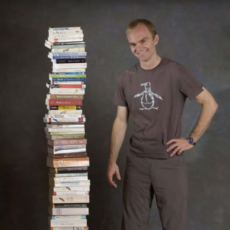 Noah Strycker with stack of field guides