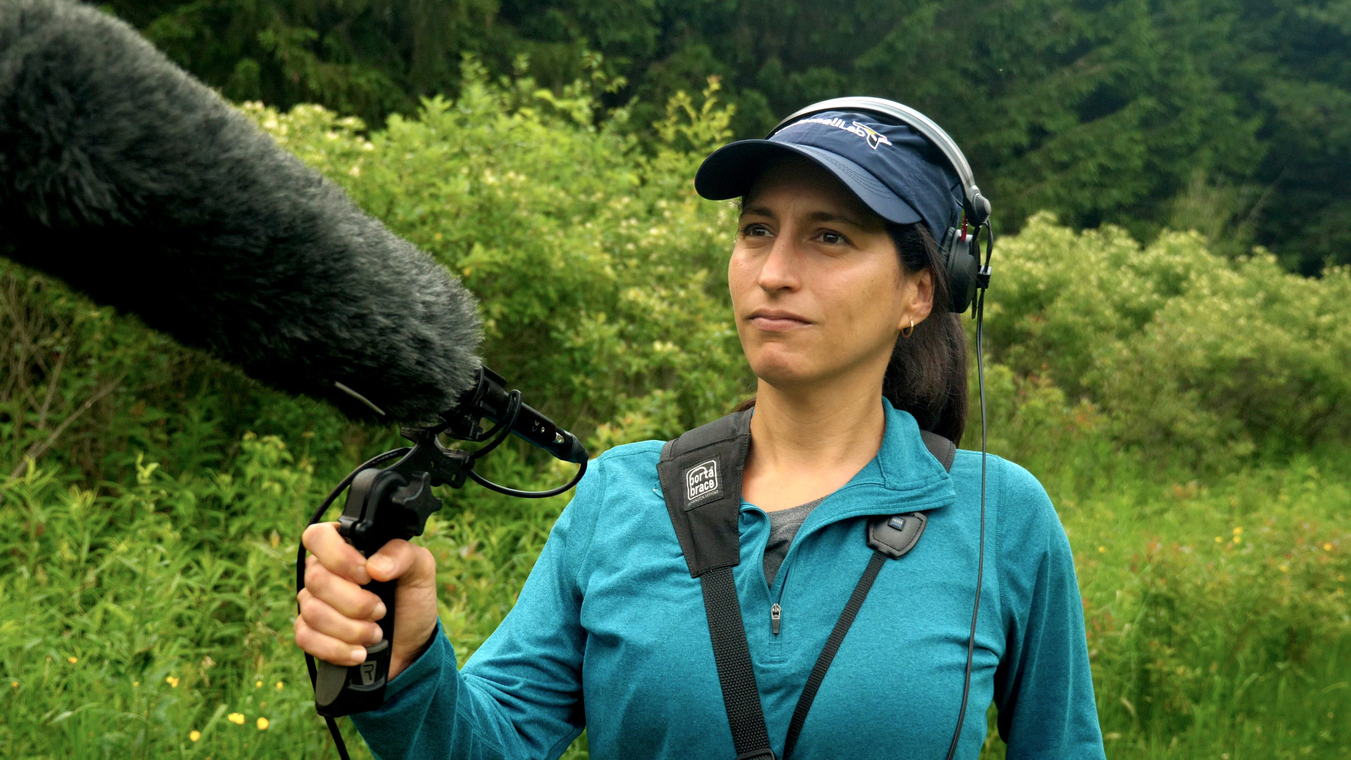 woman outdoors wearing headphones and holding a microphone